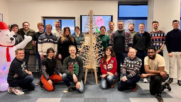 A photo of all of the Brightec team wearing Christmas jumpers, with a christmas tree in the centre