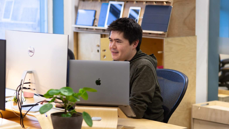 A photo of Dave working at his desk, surrounded by devices